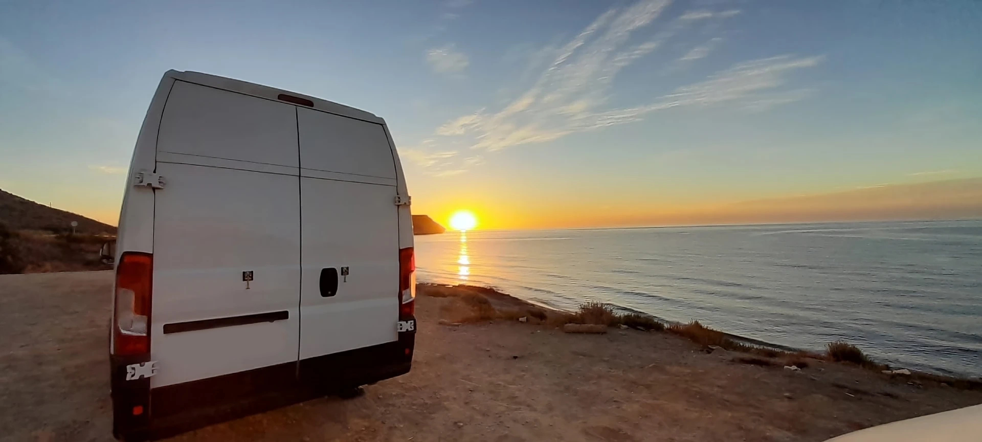 Imagen del banner principal de la pagina de camperización de stvans, en ella se puede ver una furgoneta camperizada estando de fondo un amanecer sobre la playa.